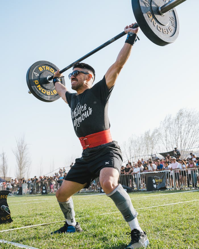 A determined athlete lifting weights outdoors during a competition, showcasing strength and focus.